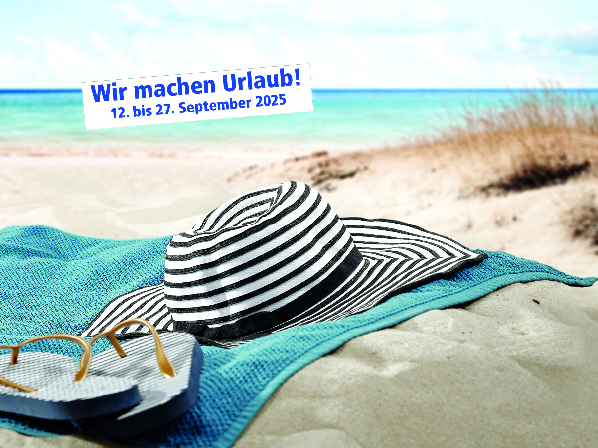 Strandbild in den Dünen mit Handtuch und Sonnenhut auf dem Sand..